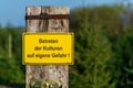 Closeup, of a yellow warning sign with German text `Entering the crops at your own risk`