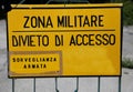 Yellow sign at military zone in italy and text that means Milita