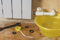 A yellow water basin and a set of tools near a leaking radiator. Accident of the heating system of a private house.