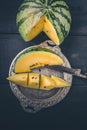 Yellow watermelon, slice of watermelon on a silver plate and knife on a dark wooden background. Vertical shot Royalty Free Stock Photo