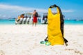 Yellow waterproof shoulder bag with sunglasses on beach sand at