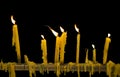 Yellow wax candles flame candlelight and drippings on brass rail.