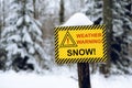 Yellow weather warning snow sign in the out of focus forest background