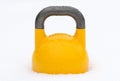 Yellow weight training kettlebell covered with water droplets outside in the snow