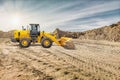 A yellow wheeled bulldozer or loader is working on a construction site, moving dirt and preparing the ground under a clear sky Royalty Free Stock Photo