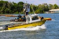 A yellow and white boat sailing through the vast green river water on the Savannah River with lush green trees and grass