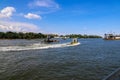 A yellow and white boat sailing through the vast green river water on the Savannah River with lush green trees and grass