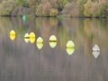 Yellow and white buoys floating in the current on the water surface of a river Royalty Free Stock Photo