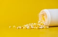 Yellow and white capsules pill spilled out from plastic bottle container. Healthcare, antibiotics drug resistance, pharmacy and Royalty Free Stock Photo