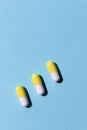 Yellow white capsules pills blue paper background Royalty Free Stock Photo