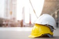 Yellow and white hard safety wear helmet hat in the project at construction site building on concrete floor on city with sunlight. Royalty Free Stock Photo