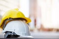 Yellow and white hard safety wear helmet hat in the project at construction site building on concrete floor on city with sunlight.