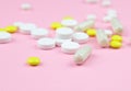 Yellow and white pills and capsules on a pink background. Medical background. Royalty Free Stock Photo