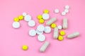 Yellow and white pills and capsules on a pink background. Medical background. Royalty Free Stock Photo