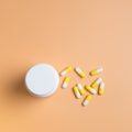 Yellow and white pills, tablets and white bottle on orange background Royalty Free Stock Photo