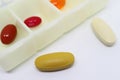 Yellow and White Pills on White Background with Pill Organizer Case in the Backdrop Royalty Free Stock Photo