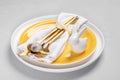 Yellow white plates, white napkin, gold cutlery and quail egg, ceramic bunny on them. Easter table. Royalty Free Stock Photo