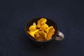 Yellow wild forest chanterelles in the clay pipkin dish with white handle on black background Royalty Free Stock Photo