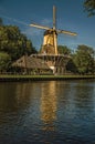 Yellow windmill next to wide canal on sunset at Weesp