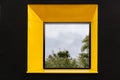 Yellow window on black facade with reflection of green tree on. Royalty Free Stock Photo