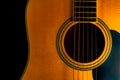 Yellow wooden acoustic guitar body with sound hole and strings on black studio background. Stringed plucked musical Royalty Free Stock Photo