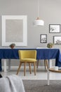 Yellow wooden chair at table with blue cloth in modern dining room interior with mockup Royalty Free Stock Photo