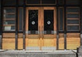 Yellow wooden entrance door with horizontal handles in yellow wooden and green painted plank wall Royalty Free Stock Photo