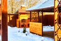 Yellow wooden gazebo with brick grill or barbecue in the yard on a Sunny winter day