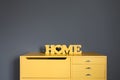 Yellow wooden inscription `house` on a yellow vintage wooden chest of drawers