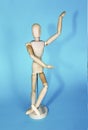 Yellow wooden maniken is dancing and doing poses on blue background