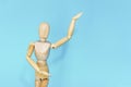 Yellow wooden maniken is dancing and doing poses on blue background