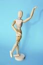 Yellow wooden maniken is dancing and doing poses on blue background