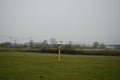 Yellow wooden post with black mark on pasture. Stadtrandhof, 12529 Schoenefeld, Germany