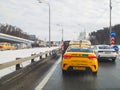 A yellow Yandex taxi car is driving in a traffic jam on a motorway.