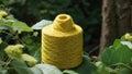 Yellow yarn cone in nature surrounded by green leaves depicting sustainability and green fashion