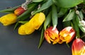 Yellow, yellow-orange two-color tulips and verba branches on a dark gray background