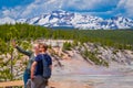 YELLOWSTONE, MONTANA, USA JUNE 02, 2018: Couple taking selfies with pools of colorfully colored water behind in Norris