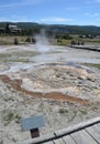 YELLOWSTONE NATIONAL PARK, WYOMING - JUNE 8, 2017: Anemone Geyser in Upper Geyser Basin With Old Faithful Inn in the Distance Royalty Free Stock Photo