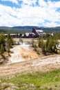 Yellowstone, Wyoming, USA, May 25, 2021, Tourists at the Firehole river and the Old Faithful Inn at the Upper Gyser Basin Royalty Free Stock Photo