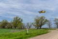 Yelow crop duster airplane flies over the farm field and road Royalty Free Stock Photo