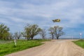 Yelow crop duster airplane flies over the farm field and road Royalty Free Stock Photo