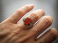 Yemeni red akik agate stone. Male hand with ring on ring finger with dark background