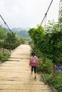 Yen Bai, Vietnam - Sep 18, 2016: Vietnamese Hmong ethnic minority girl walking home on old small chain wooden bridge from school w Royalty Free Stock Photo