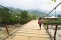 Yen Bai, Vietnam - Sep 18, 2016: Vietnamese Hmong ethnic minority girl walking home on old small chain wooden bridge from school w Royalty Free Stock Photo