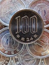 100 yen lies on a pyramid of Japanese 1 yen coins. Close up. View from above. Catchy bright vertical illustration. News about the Royalty Free Stock Photo