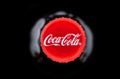 Yerevan, Armenia, May 10 2023: Coca Cola logo on a cork cap Black bottle of Coca-Cola sparkling water. Top view. Classic company