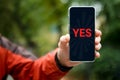 Yes concept. A smartphone with the word yes on the smartphone screen in a man& x27;s hand. Message using a mobile phone Royalty Free Stock Photo