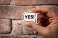 Yes Concept. Speech bubble with text in hand on brick background Royalty Free Stock Photo