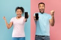 Yes. Happy black couple showing smarphones with blank screens and shaking clenched fists, mockup, banner