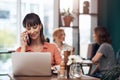 Yes this is her speaking. an attractive middle aged woman talking on her cellphone while working on a laptop inside of a Royalty Free Stock Photo